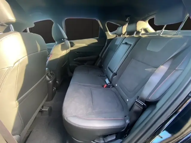 Vue intérieure du côté arrière droit du Hyundai Tucson 1.6 Hybrid noir, montrant les sièges en cuir et alcantara avec surpiqûres rouges.
