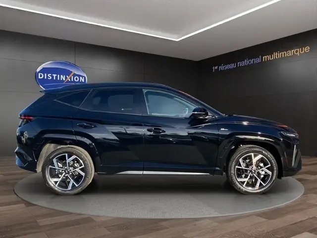 Profil côté gauche d’un Hyundai Tucson 1.6 Hybrid N Line Creative noir, avec jantes alliage et toit spoiler visible.