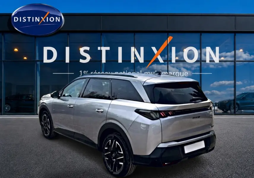 Peugeot 5008 Hybrid 145 gris artense en 3/4 arrière droit, avec vitres arrière surteintées et jantes alu noires.