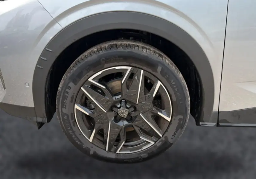 Gros plan sur la roue arrière droite d’un Peugeot 5008 gris Artense avec jante alu noire et argentée design moderne.