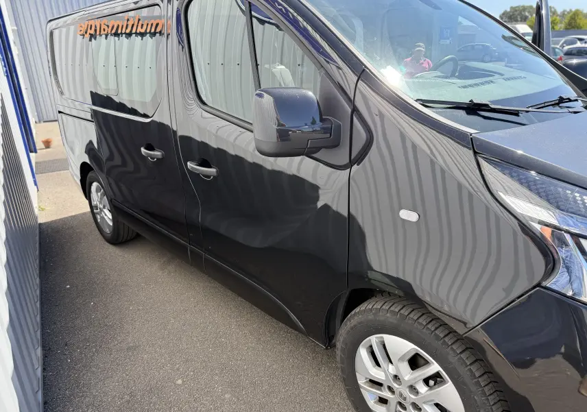 Vue de côté droit avant d’un Renault Trafic cabine approfondie gris 2021 avec jantes alliage et vitres teintées.