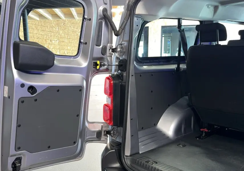 Vue intérieure arrière gauche d'un Opel Vivaro Combi gris 2022, montrant la porte ouverte et les sièges en tissu noir.