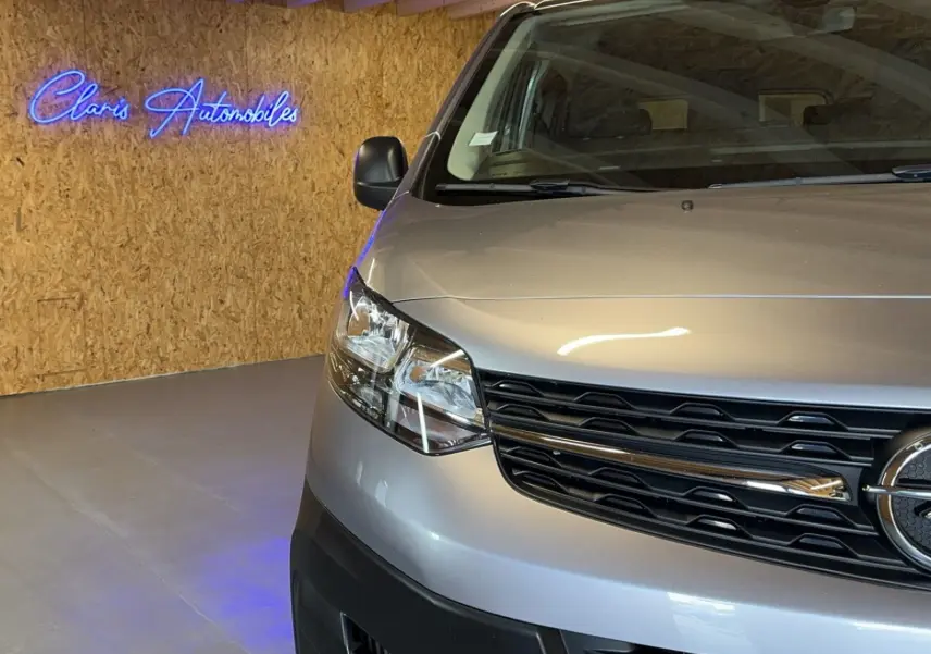 Vue de face partielle côté gauche d'un Opel Vivaro Combi gris 2022 avec calandre noire et phares modernes.