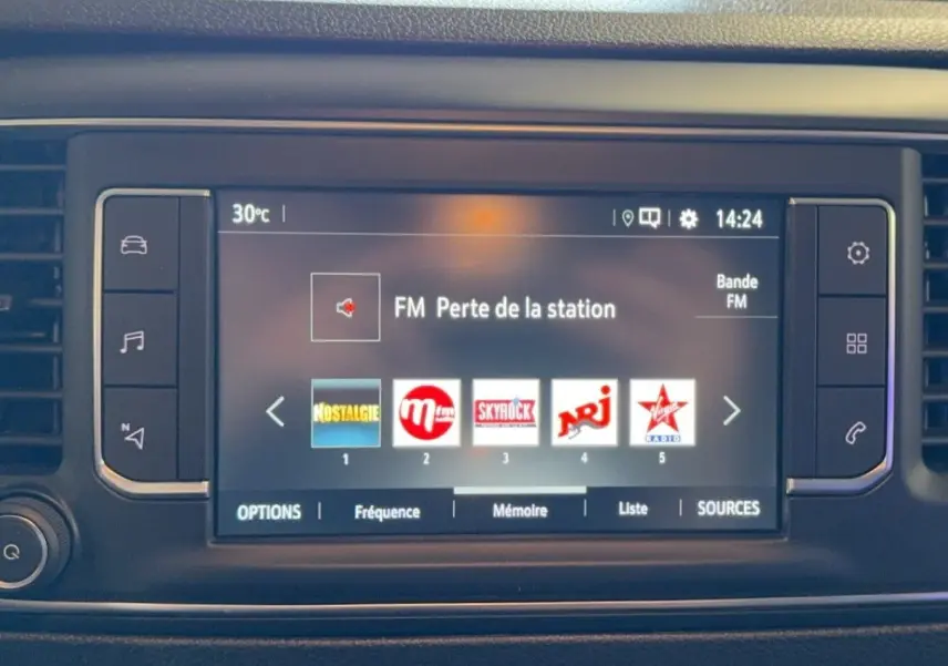 Écran tactile central du tableau de bord de l'Opel Vivaro Combi 2022 affichant les stations radio FM avec commandes latérales.