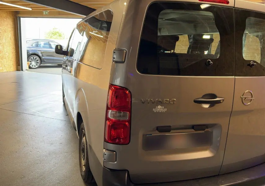Vue 3/4 arrière droite d’un Opel Vivaro Combi gris diesel 2022 avec hayon et vitres teintées.