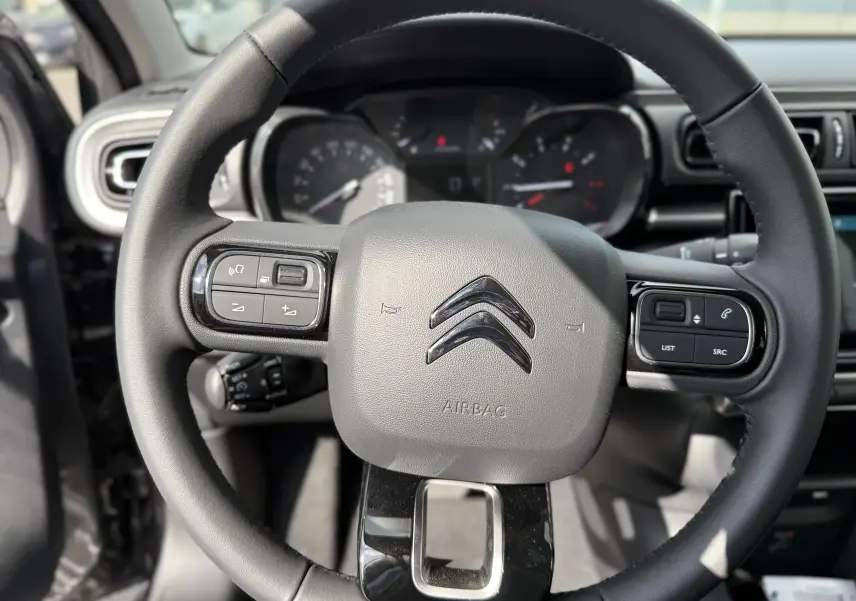 Volant en cuir avec commandes intégrées et logo Citroën, vue rapprochée de l'habitacle de la C3 gris platinium 2024.
