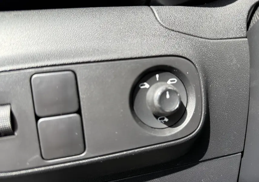 Gros plan sur le bouton de réglage des rétroviseurs dans l’habitacle noir d’une Citroën C3 gris platinium 2024.