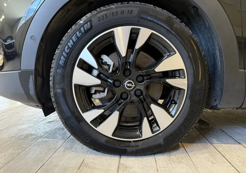 Gros plan sur la roue avant gauche noire métal de l'Opel Grandland X 1.6 Hybrid Turbo avec jante alliage bicolore.