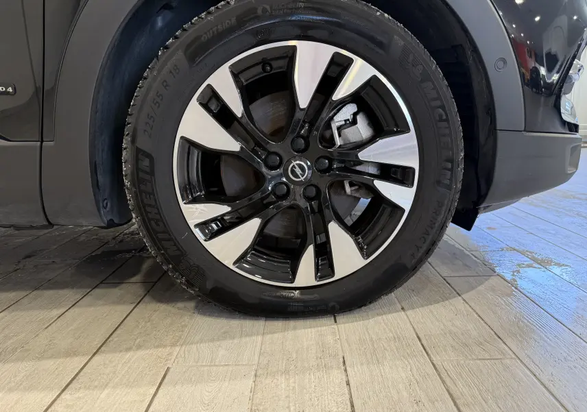 Gros plan sur la roue avant droite noire métal de l'Opel Grandland X 1.6 Hybrid Turbo avec jante alliage bicolore.