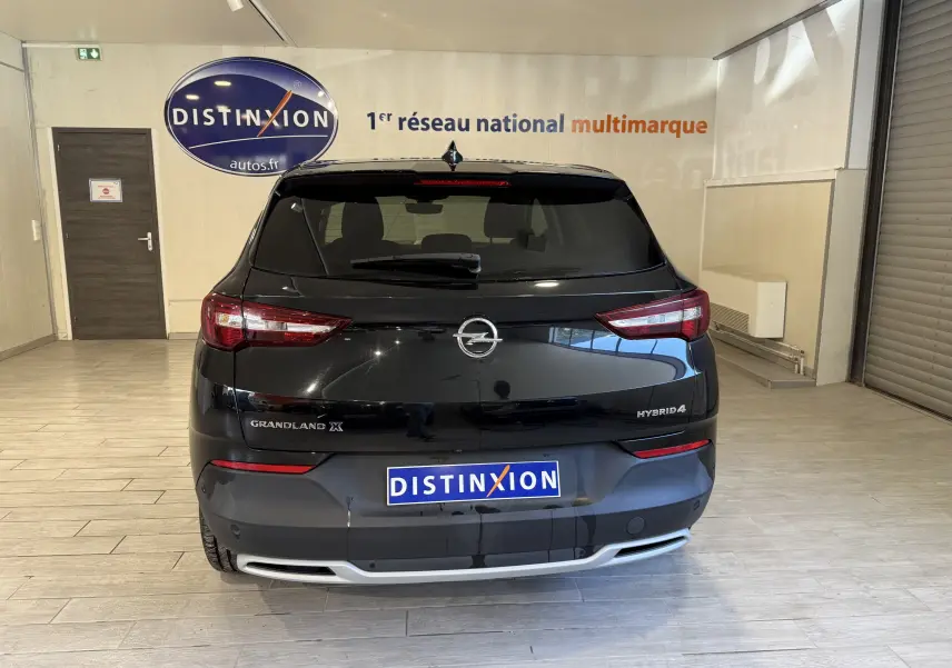 Vue arrière d'un Opel Grandland X noir métal hybride rechargeable, avec logo et badges visibles en intérieur showroom.