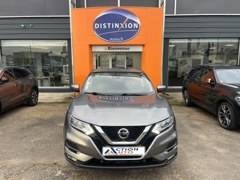 Nissan Qashqai gris Squale vu de face, garé devant un concessionnaire avec logo orange Distinxion.