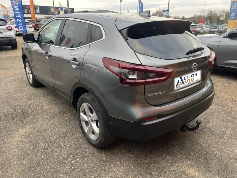 Vue 3/4 arrière droite d'un Nissan Qashqai gris Squale avec hayon teinté et attelage de remorque visible.