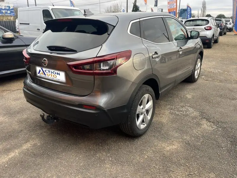 Vue 3/4 arrière droite d'un Nissan Qashqai gris Squale avec vitres teintées et attelage de remorque visible.