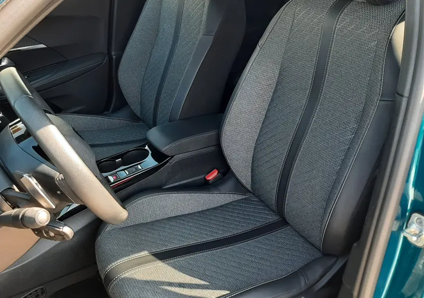 Vue intérieure côté conducteur du PEUGEOT 2008 Hybrid 145 Allure en Bleu Obsession, sièges tissu gris avec surpiqûres noires.
