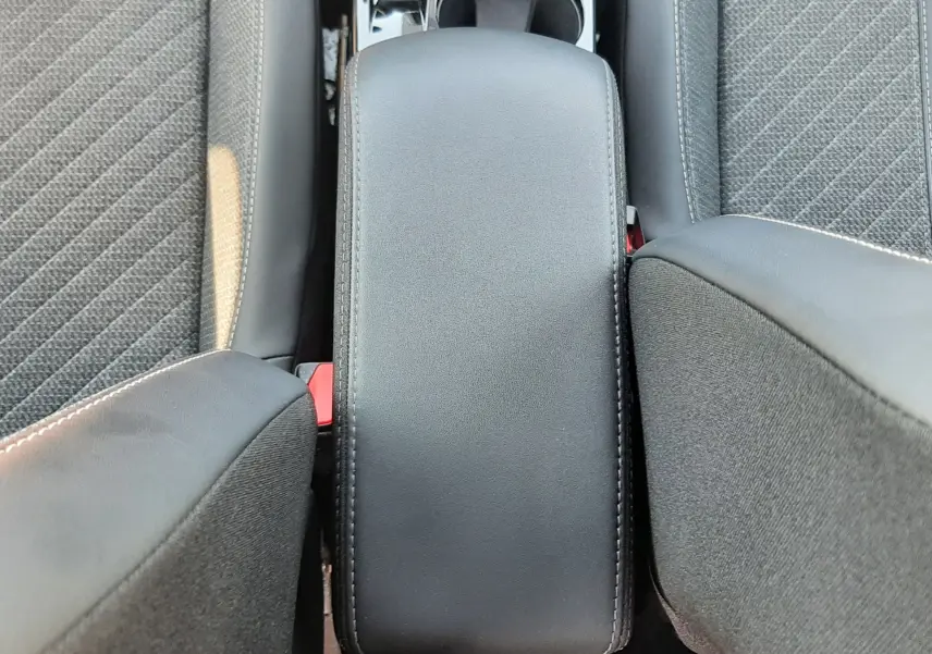 Vue plongeante sur l'accoudoir central noir et les sièges gris du Peugeot 2008 Hybrid 145 Allure 2025.