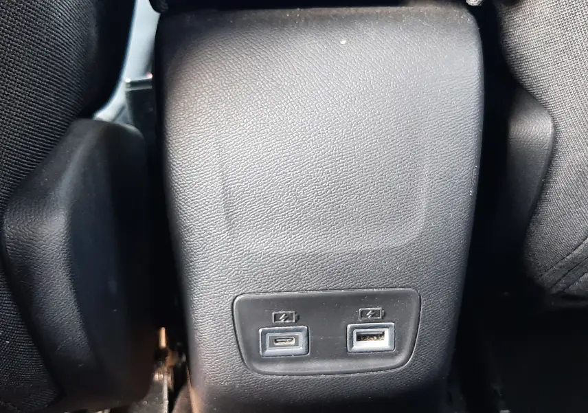 Vue rapprochée de la console centrale arrière noire avec ports USB-C et USB-A dans un Peugeot 2008 Hybrid 145 Allure 2025.