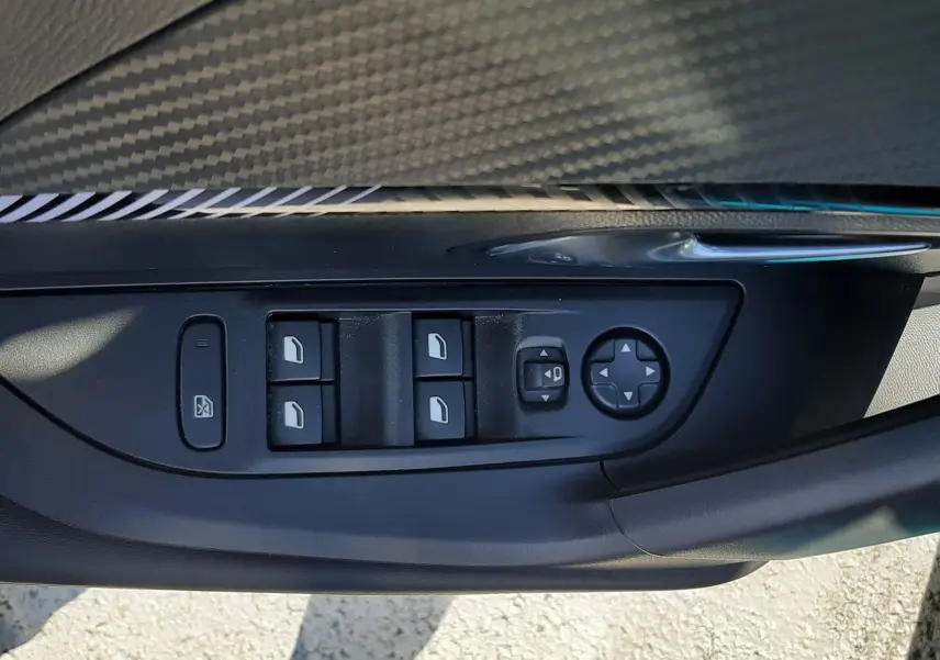 Gros plan sur la commande des vitres et rétroviseurs côté gauche intérieur d’une Peugeot 2008 Bleu Obsession 2025.