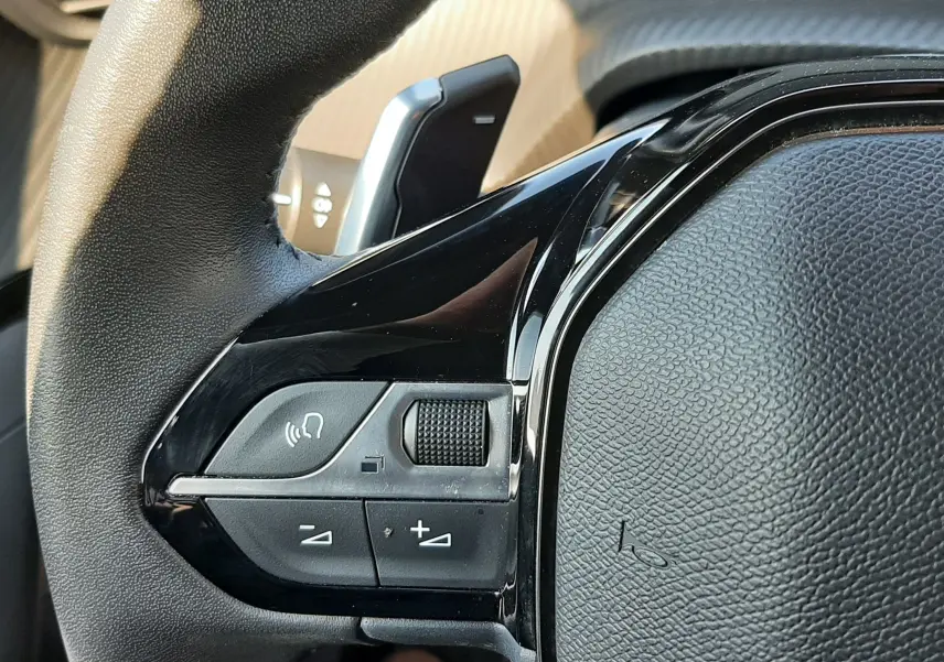 Gros plan sur la partie gauche du volant noir du Peugeot 2008 Hybrid 145 Allure 2025, avec commandes intégrées.