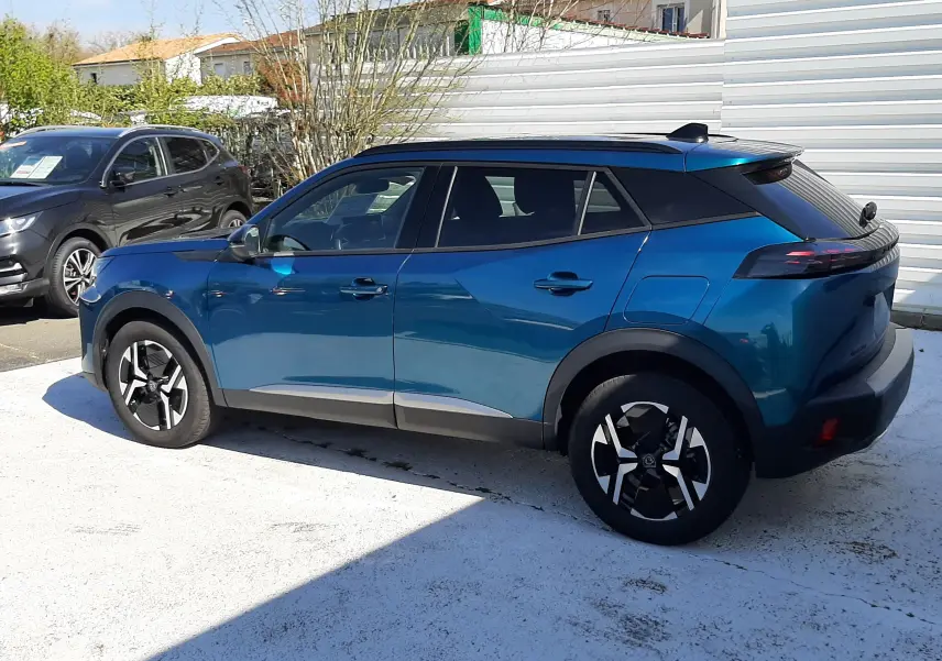 Peugeot 2008 Hybrid 145 Allure bleu obsession vue de profil côté gauche, toit noir et jantes bicolores distinctives.