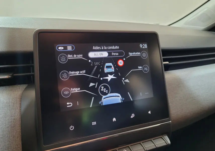 Écran tactile central de la Renault Clio gris foncé montrant les aides à la conduite, vue intérieure avant.