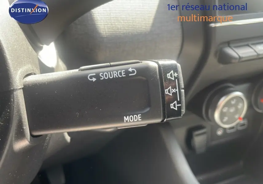 Gros plan sur la commande au volant de la Renault Clio blanche 2025, montrant les boutons source et mode.