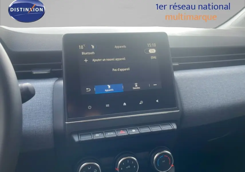 Vue intérieure centrée sur l’écran tactile et la console centrale de la Renault Clio blanche, avec détails des commandes climatisation.