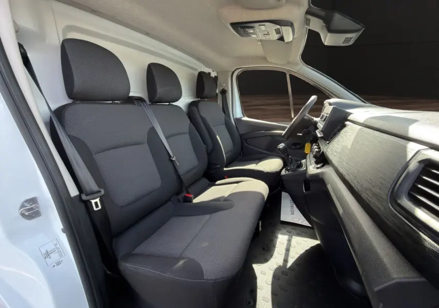 Vue intérieure côté conducteur du Renault Trafic Fourgon blanc 2024, montrant les sièges avant et le tableau de bord.