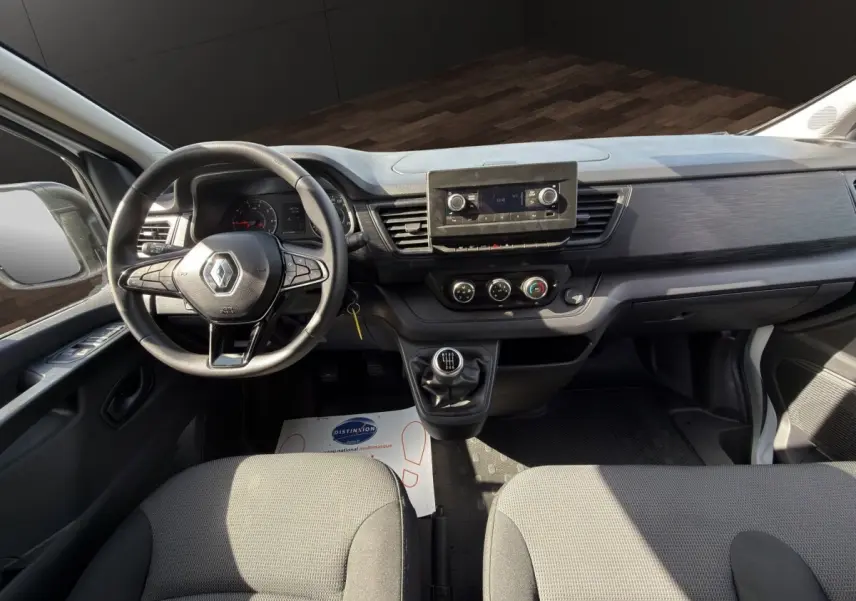 Vue intérieure avant du Renault Trafic Fourgon blanc 2024, montrant le volant multifonctions et la console centrale avec écran.