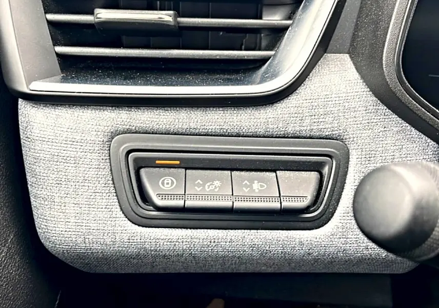 Détail des commandes d’éclairage et verrouillage sur tableau de bord gris texturé d’une Renault Clio V blanche.