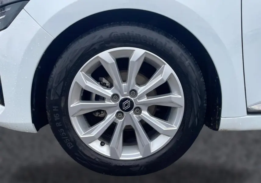 Gros plan sur la roue avant gauche de la Renault Clio V blanche, avec jante alliage 16 pouces et logo central.