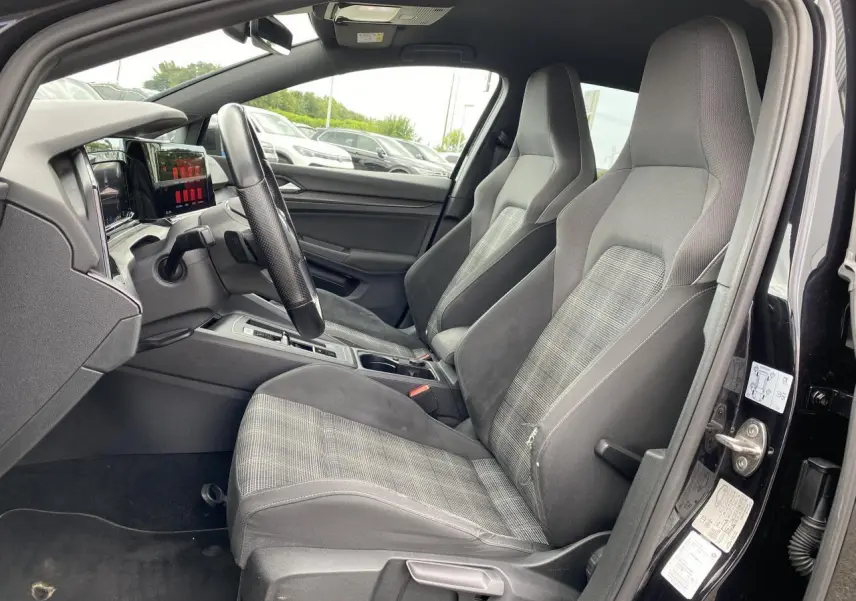 Intérieur de la Volkswagen Golf VIII GTD 2022, vue côté gauche, sièges sport tissu gris et tableau de bord moderne.