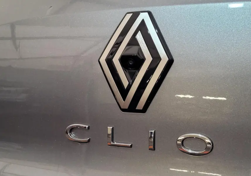 Gros plan sur le logo Renault et le lettrage Clio sur la malle arrière d'une voiture gris foncé.