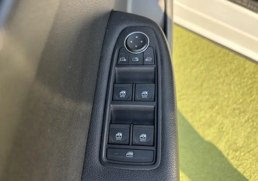 Gros plan sur les commandes des vitres électriques côté conducteur du Renault Arkana blanc glacier 2025.
