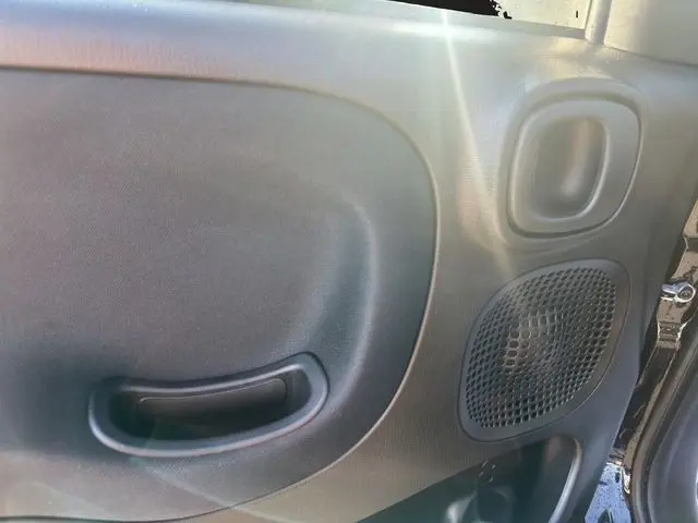 Détail intérieur côté droit de la porte noire d'une FIAT Panda 1.0 FireFly 2025, avec poignée et haut-parleur intégrés.