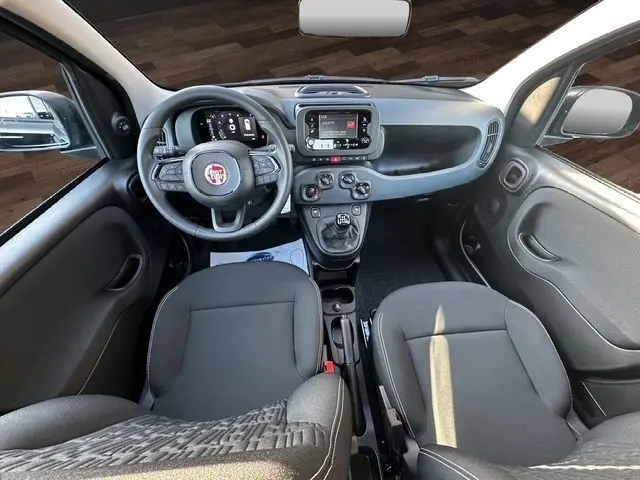 Vue intérieure avant de la Fiat Panda 2025 noire, montrant le tableau de bord, volant multifonction et écran central tactile.
