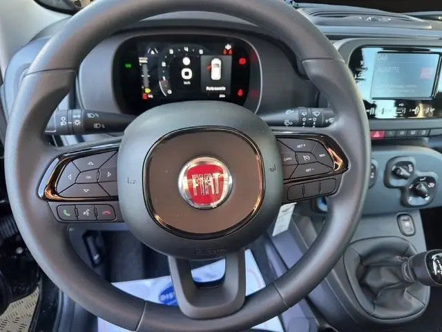 Vue rapprochée du volant noir de la Fiat Panda 1.0 FireFly 2025 avec tableau de bord digital et commandes au volant.