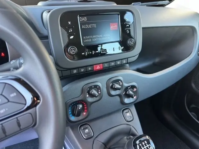 Vue intérieure du tableau de bord de la Fiat Panda noire 2025, avec écran tactile et commandes climatisation visibles.