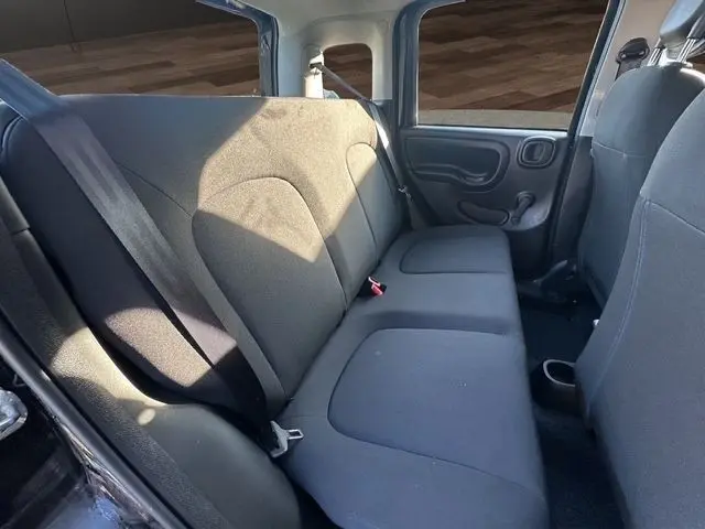 Vue intérieure arrière droite de la Fiat Panda 2025 noire, montrant la banquette arrière en tissu gris et les ceintures de sécurité.
