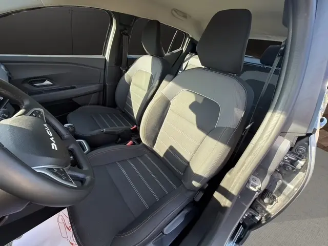 Vue intérieure côté conducteur de la Dacia Sandero Stepway gris foncé, montrant les sièges avant et le volant multifonctions.
