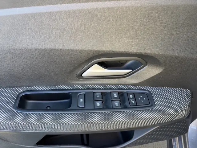 Gros plan sur la commande des vitres électriques et la poignée intérieure côté conducteur de la Dacia Sandero Stepway gris foncé.