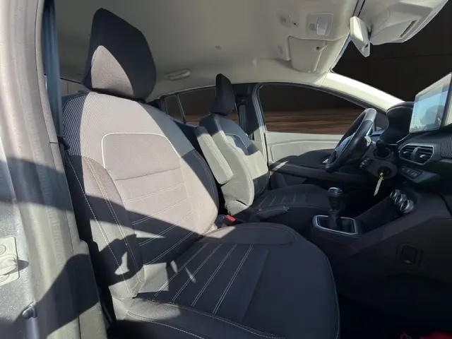 Vue intérieure côté gauche de la Dacia Sandero Stepway 2025, montrant sièges tissu noirs et tableau de bord avec écran tactile.