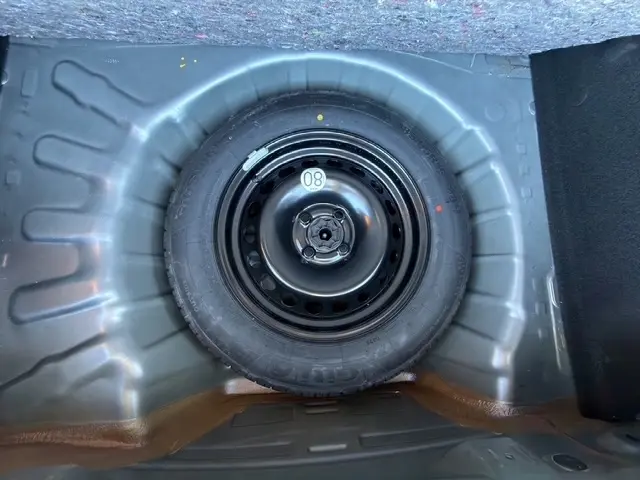 Gros plan sur la roue de secours noire logée dans le coffre d’une Dacia Sandero Stepway gris foncé 2025.