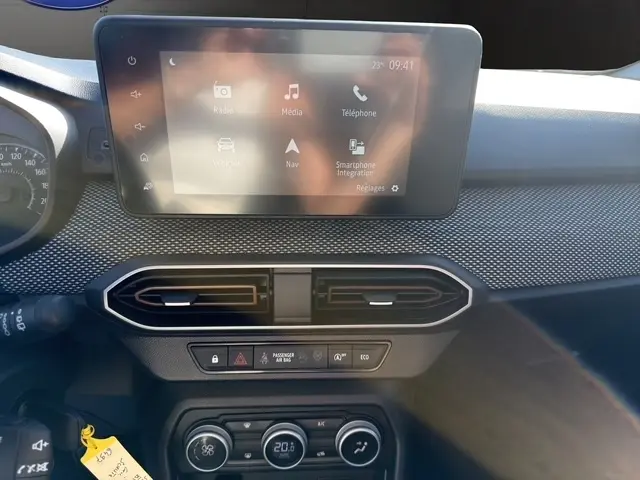 Vue rapprochée du tableau de bord gris foncé de la Dacia Sandero Stepway 2025 avec écran tactile central et commandes climatisation.