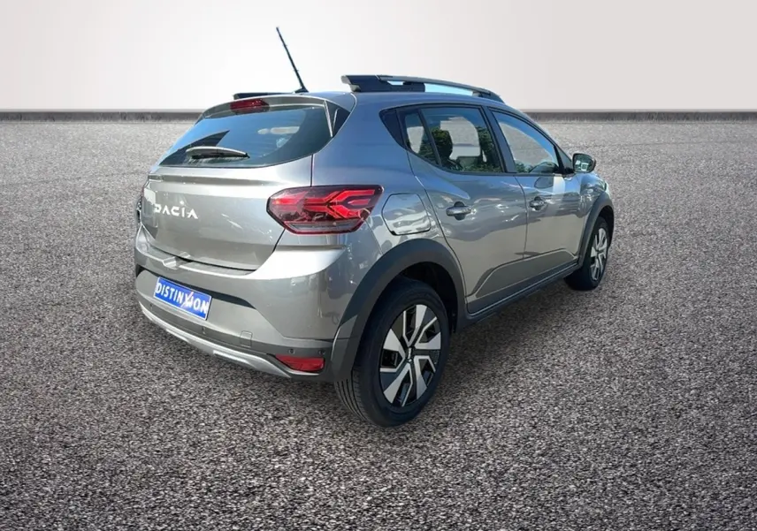Vue 3/4 arrière droite d'une Dacia Sandero Stepway gris foncé avec barres de toit et jantes alliage.