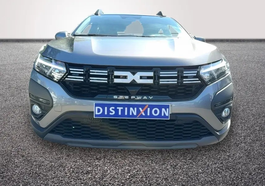 Vue frontale d'une Dacia Sandero Stepway gris foncé avec calandre noire et feux LED allumés.