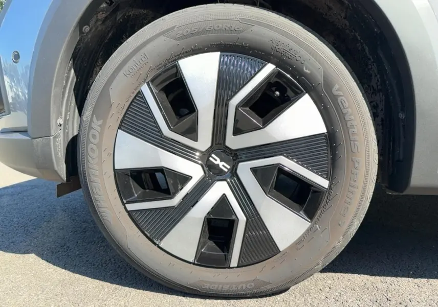 Gros plan sur la roue avant droite d'une Dacia Sandero Stepway gris foncé avec jante au design noir et argent.