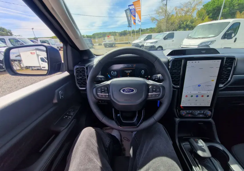 Vue intérieure du poste de conduite du Ford Ranger Super Cabine bleu Lightning, avec volant multifonction et grand écran tactile vertical.
