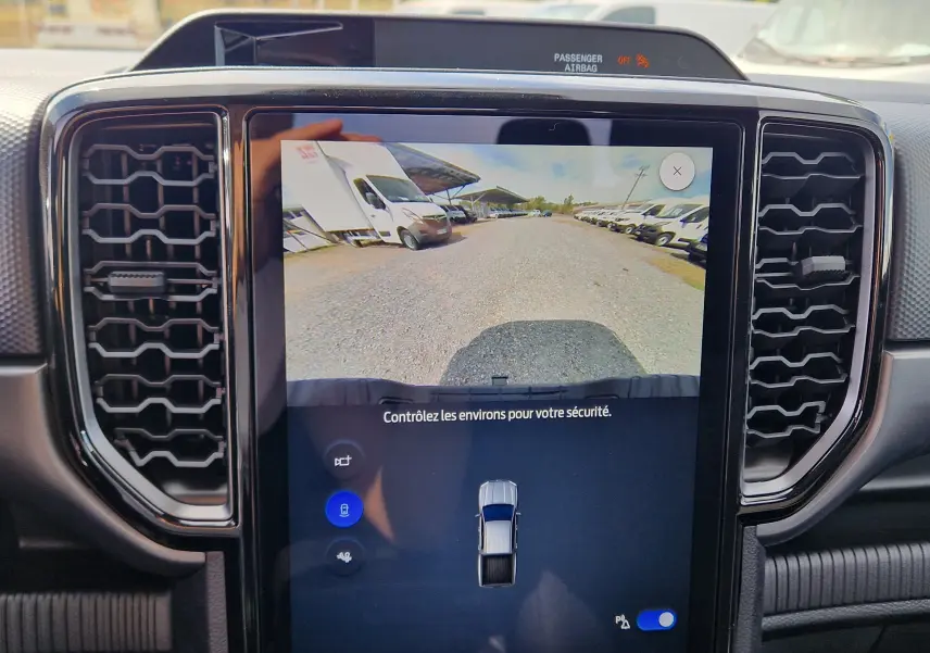Vue intérieure sur l'écran tactile central du Ford Ranger bleu Lightning, affichant la caméra de recul et les aérateurs noirs.