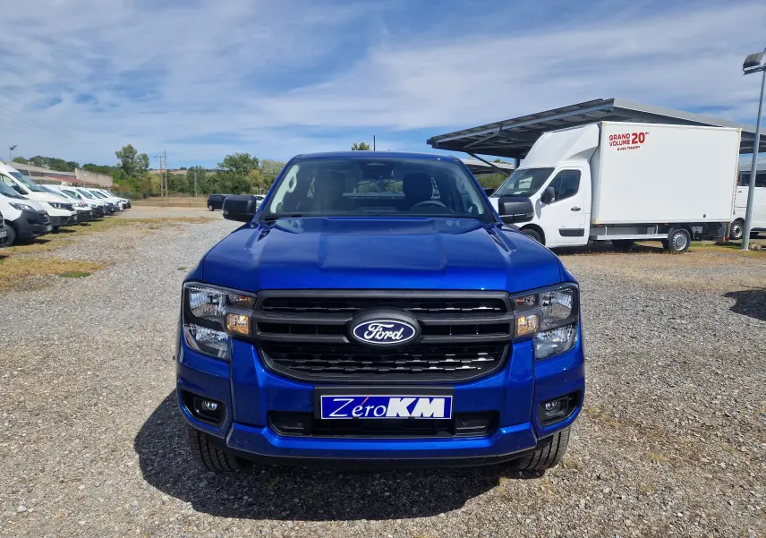 Vue de face du Ford Ranger Super Cabine bleu Lightning avec calandre noire et plaque "Zero KM" sur un parking extérieur.