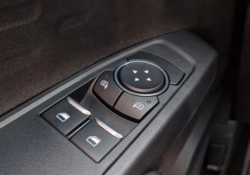 Gros plan sur les commandes de réglage des rétroviseurs et des vitres côté conducteur du Ford Ranger Super Cabine bleu Lightning.